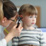 Pediatrician examining a child's ear for signs of infection